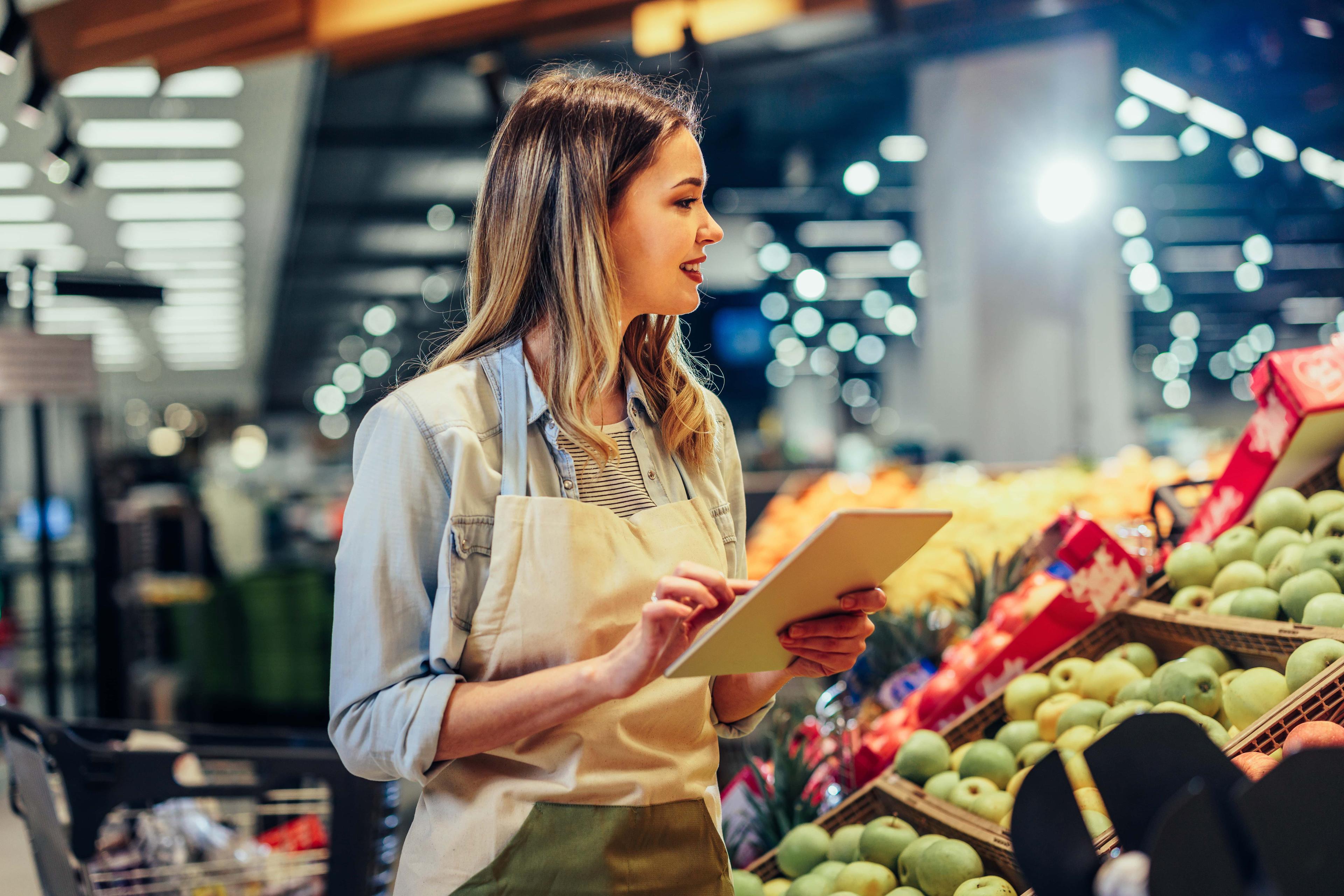 retail worker taking inventory of produce section in grocery store