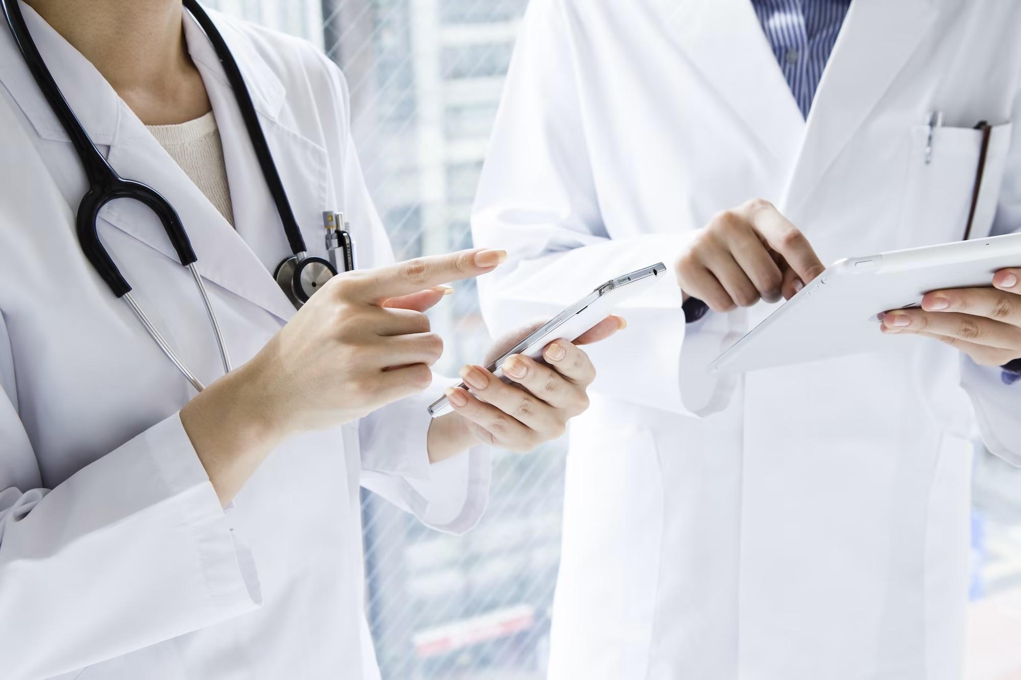 healthcare workers reviewing data on phones and tablets while standig in a hospital
